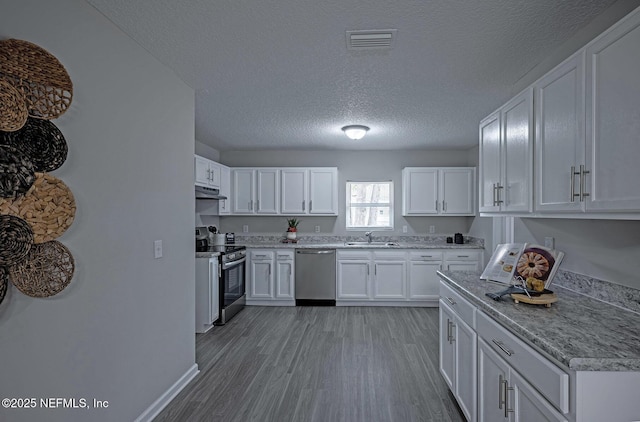 kitchen featuring appliances with stainless steel finishes, light hardwood / wood-style floors, sink, and white cabinets