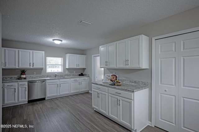 kitchen with hardwood / wood-style floors, white cabinetry, sink, stainless steel dishwasher, and a textured ceiling