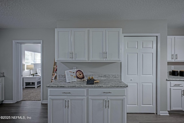 kitchen with dark hardwood / wood-style flooring, white cabinets, and a textured ceiling