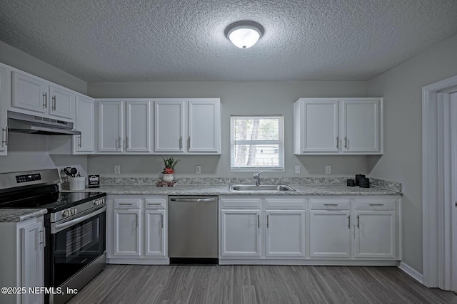 kitchen featuring hardwood / wood-style flooring, white cabinetry, appliances with stainless steel finishes, and sink