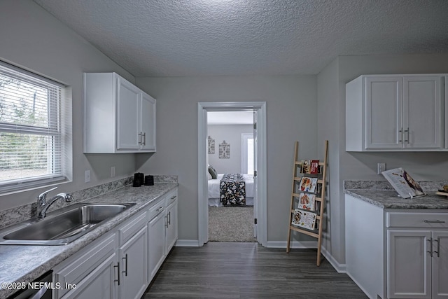 kitchen with sink, dishwasher, white cabinetry, dark hardwood / wood-style floors, and a textured ceiling