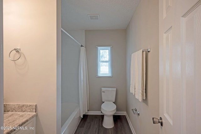 full bathroom with hardwood / wood-style floors, vanity, a textured ceiling, toilet, and shower / bath combo with shower curtain