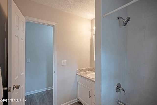 bathroom with vanity, tiled shower / bath combo, a textured ceiling, and hardwood / wood-style flooring