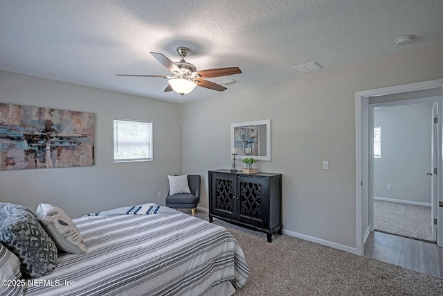 carpeted bedroom featuring ceiling fan and a textured ceiling