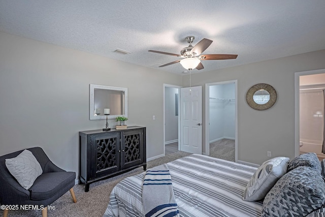 carpeted bedroom featuring ensuite bath, a spacious closet, a textured ceiling, a closet, and ceiling fan