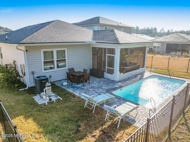 rear view of property featuring a patio area, central AC unit, a yard, a fenced in pool, and a sunroom