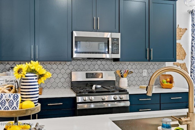 kitchen featuring tasteful backsplash, sink, blue cabinetry, and appliances with stainless steel finishes