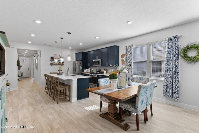 dining area with light hardwood / wood-style floors, sink, and a textured ceiling