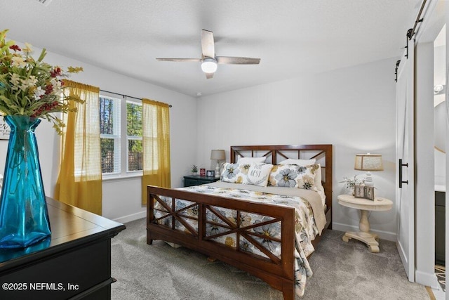 carpeted bedroom with ceiling fan and a barn door