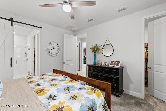 carpeted bedroom with connected bathroom, a barn door, and ceiling fan