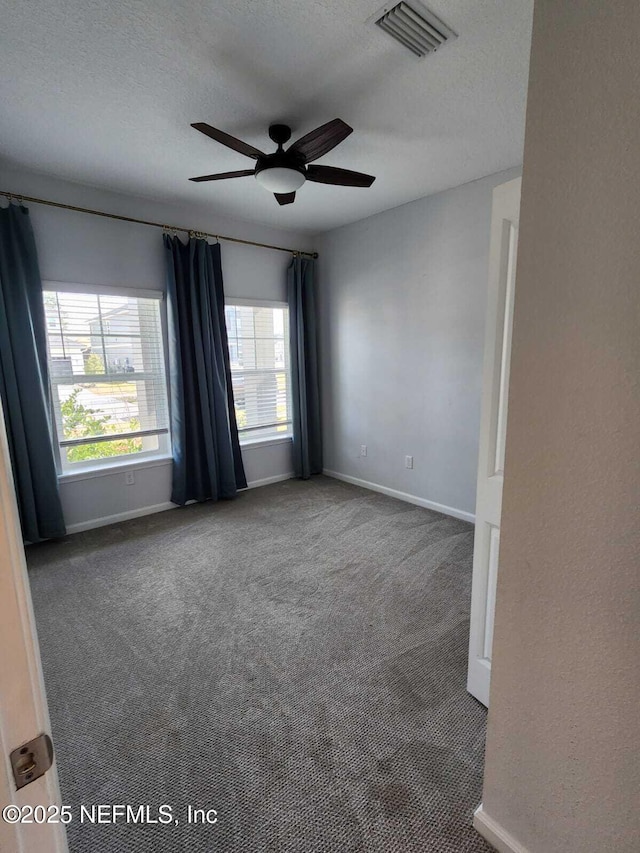 carpeted spare room with ceiling fan and a textured ceiling