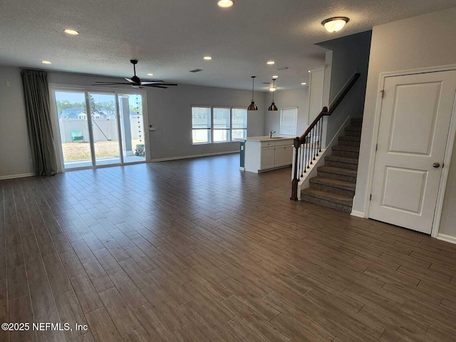 unfurnished living room featuring ceiling fan, sink, dark hardwood / wood-style floors, and a textured ceiling