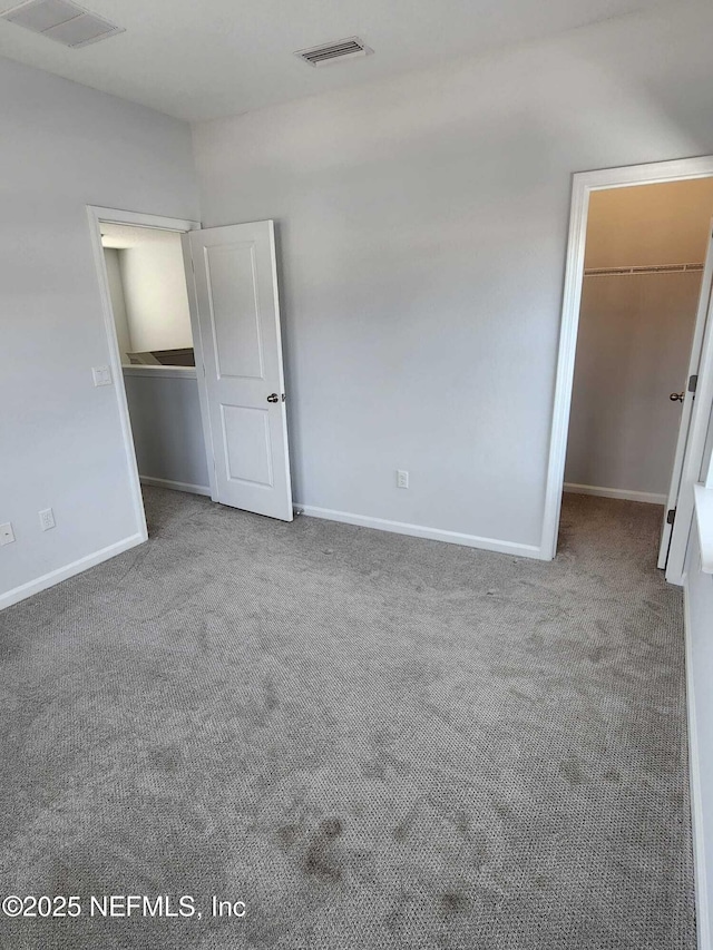 unfurnished bedroom featuring a walk in closet, carpet floors, and a closet