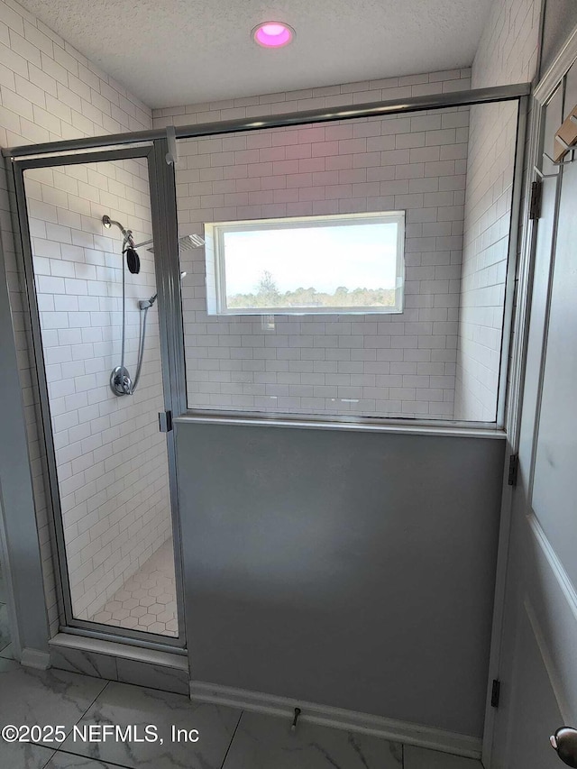 bathroom with a shower with door and a textured ceiling