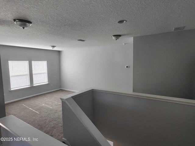 carpeted spare room featuring a textured ceiling