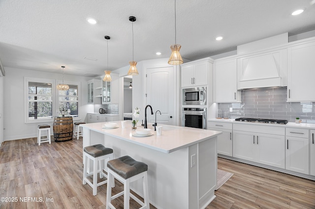 kitchen featuring an island with sink, white cabinets, and appliances with stainless steel finishes