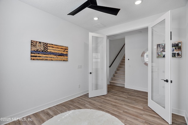 empty room featuring ceiling fan, a textured ceiling, light wood-type flooring, and french doors