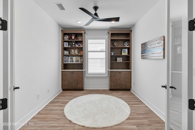 unfurnished room with ceiling fan, a textured ceiling, and light wood-type flooring