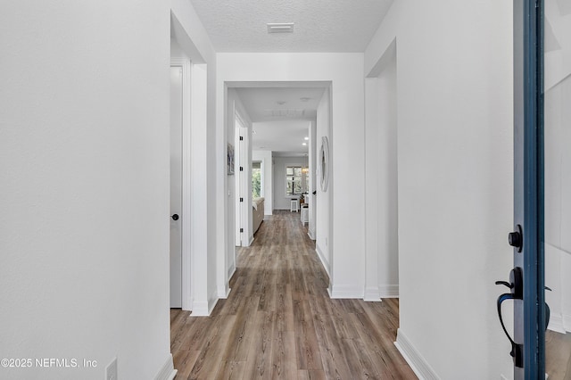 hall featuring a textured ceiling and light wood-type flooring