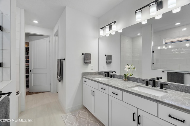 bathroom with a tile shower and vanity