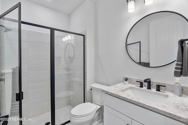 bathroom featuring vanity, toilet, and a shower with shower door