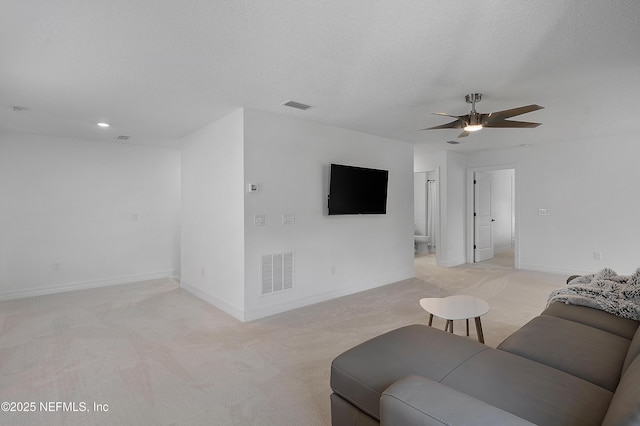 living room featuring ceiling fan, light carpet, and a textured ceiling