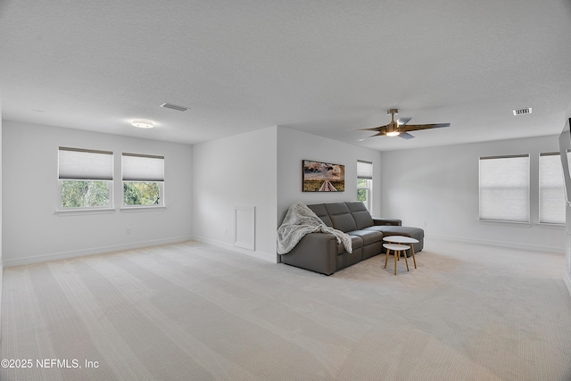 carpeted living room with ceiling fan, a wealth of natural light, and a textured ceiling