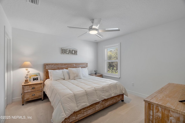 bedroom with ceiling fan, light carpet, and a textured ceiling