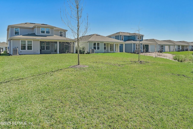 rear view of property with central AC unit and a lawn