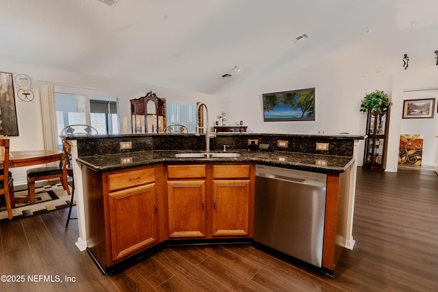 kitchen with sink, dark wood-type flooring, dishwasher, an island with sink, and vaulted ceiling