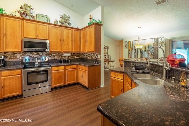 kitchen featuring pendant lighting, sink, stainless steel appliances, and lofted ceiling