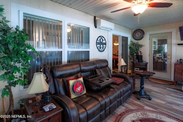 living room with wood-type flooring, an AC wall unit, and ceiling fan