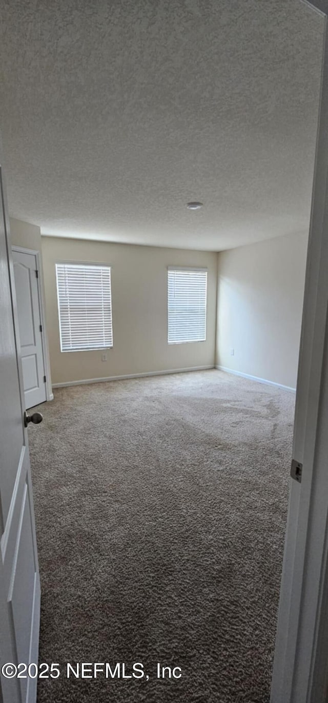 carpeted empty room with a textured ceiling