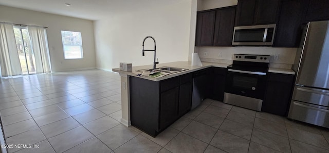 kitchen featuring appliances with stainless steel finishes, sink, light tile patterned floors, and kitchen peninsula