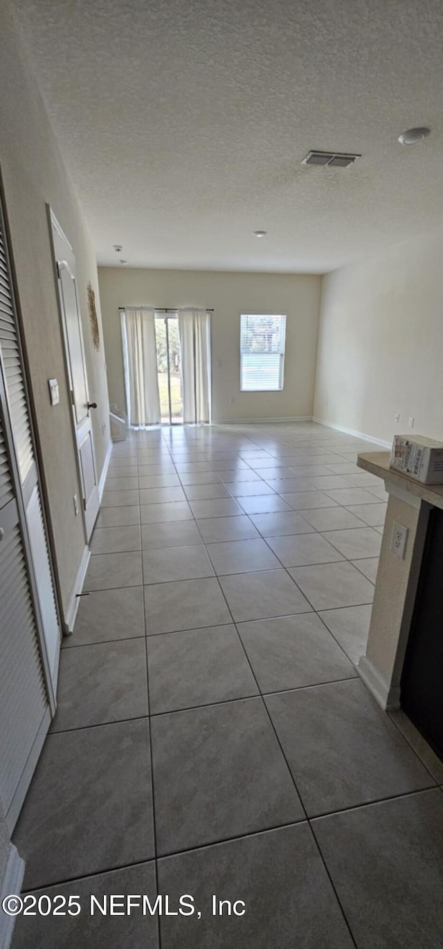 corridor featuring light tile patterned flooring and a textured ceiling