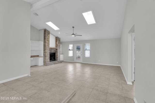 unfurnished living room featuring light tile patterned floors, ceiling fan, a skylight, high vaulted ceiling, and a brick fireplace