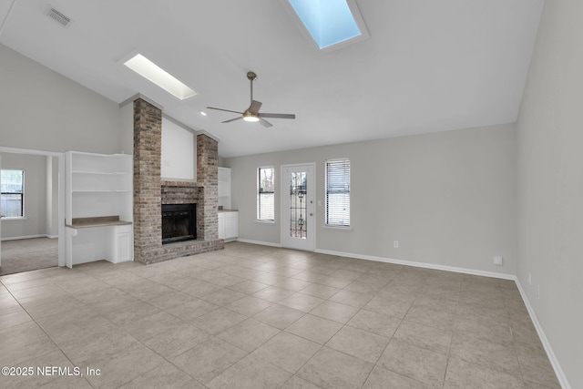 unfurnished living room featuring a fireplace, light tile patterned floors, a skylight, and ceiling fan