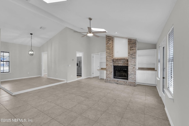 unfurnished living room with light tile patterned flooring, a brick fireplace, ceiling fan with notable chandelier, and high vaulted ceiling