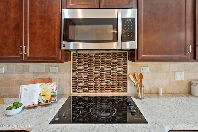 kitchen featuring light stone countertops, black electric stovetop, and backsplash