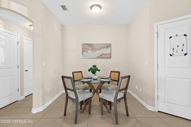 tiled dining area with a textured ceiling