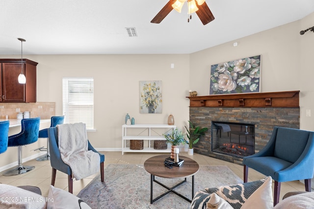 tiled living room with ceiling fan and a fireplace