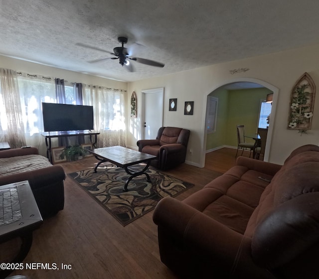 living room featuring ceiling fan, dark wood-type flooring, and a textured ceiling