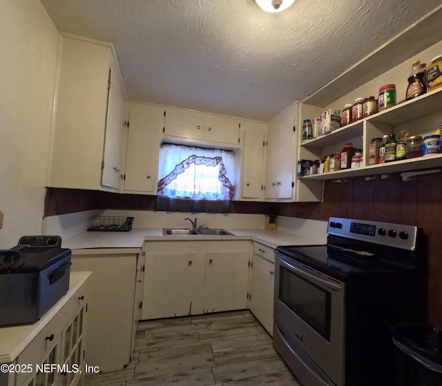 kitchen featuring sink, a textured ceiling, stainless steel range with electric cooktop, and white cabinets