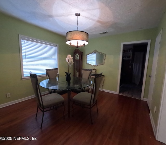 dining space with dark hardwood / wood-style flooring and a textured ceiling