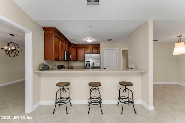 kitchen featuring decorative light fixtures, stainless steel appliances, kitchen peninsula, and a breakfast bar