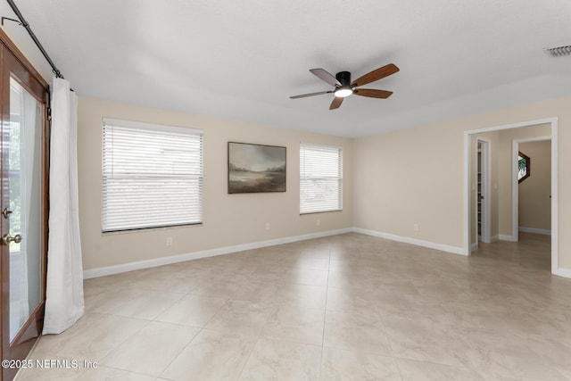 spare room with ceiling fan and light tile patterned floors