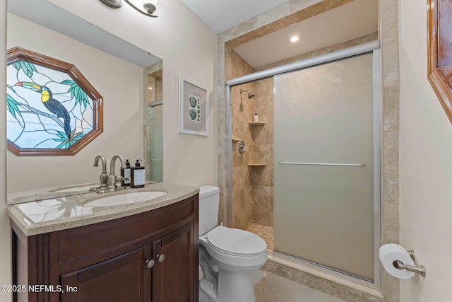 bathroom with vanity, a shower with shower door, tile patterned floors, and toilet