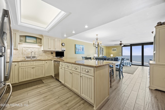 kitchen with sink, a wall of windows, backsplash, cream cabinets, and kitchen peninsula