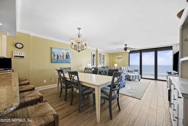 dining space with ceiling fan with notable chandelier, light hardwood / wood-style flooring, ornamental molding, and floor to ceiling windows