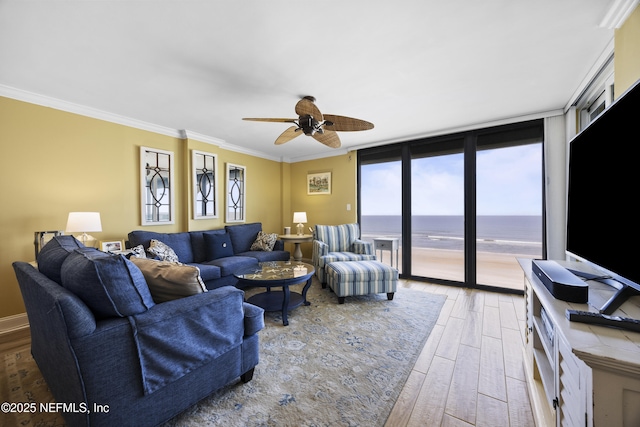 living room featuring ceiling fan, ornamental molding, wood-type flooring, and a wall of windows